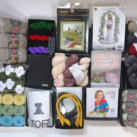 A picture taken from above of a variety of the potential prize you could receive in the Knit for Peace Lucky Dip: yarn, knitting supplies, embroidery kits and other crafting materials.